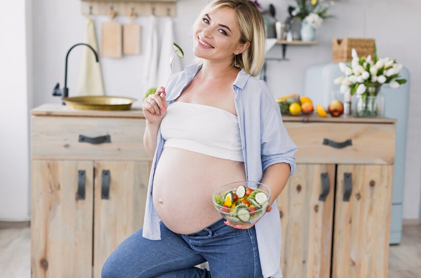 pregnant-woman-eating-salad-while-looking-camera_23-2148301931